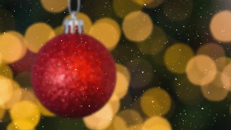 animation of snow falling over red christmas bauble and glowing spots decorations