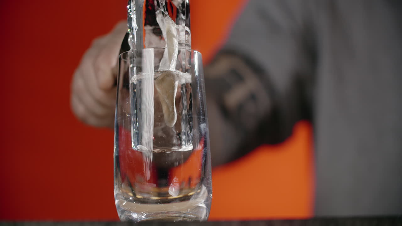 el camarero vertiendo hielo en un vaso.