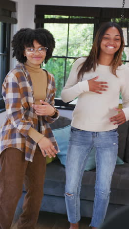 vertical video of portrait of happy diverse teenager girls dancing at home, slow motion