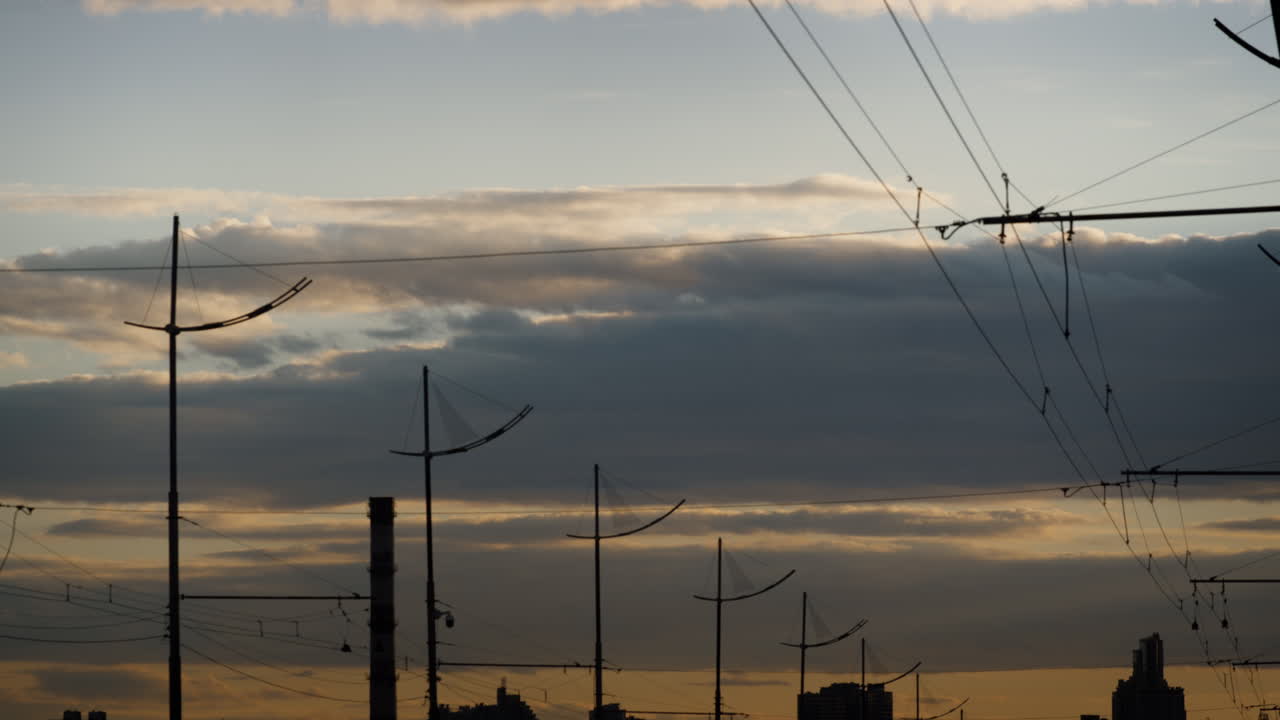 nubes grises hinchadas moviéndose sobre la ciudad a la hora de la puesta del sol. cables eléctricos linternas.