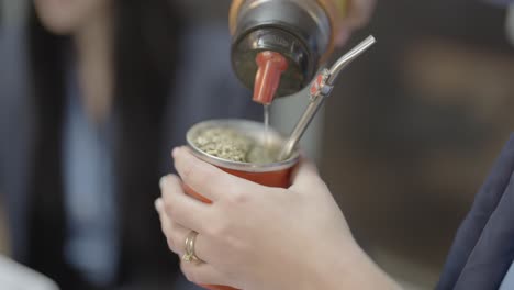 close-up of man pouring water, preparing yerba mate tea, south american tradition