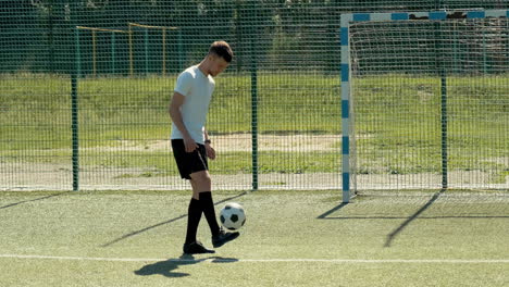 Un-Joven-Futbolista-Entrenando-Trucos-De-Estilo-Libre-Con-La-Pelota-En-Un-Campo-De-Fútbol-Callejero-En-Un-Día-Soleado
