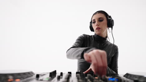 a female dj performing with headphones, mixing music on turntables in a studio