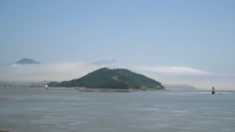 seagulls flying over the yellow sea near ganghwado island, south korea, red navigational buoy floating in yellow sea between islands, static seaside panorama