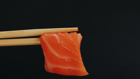 piece of salmon sashimi on chopsticks
