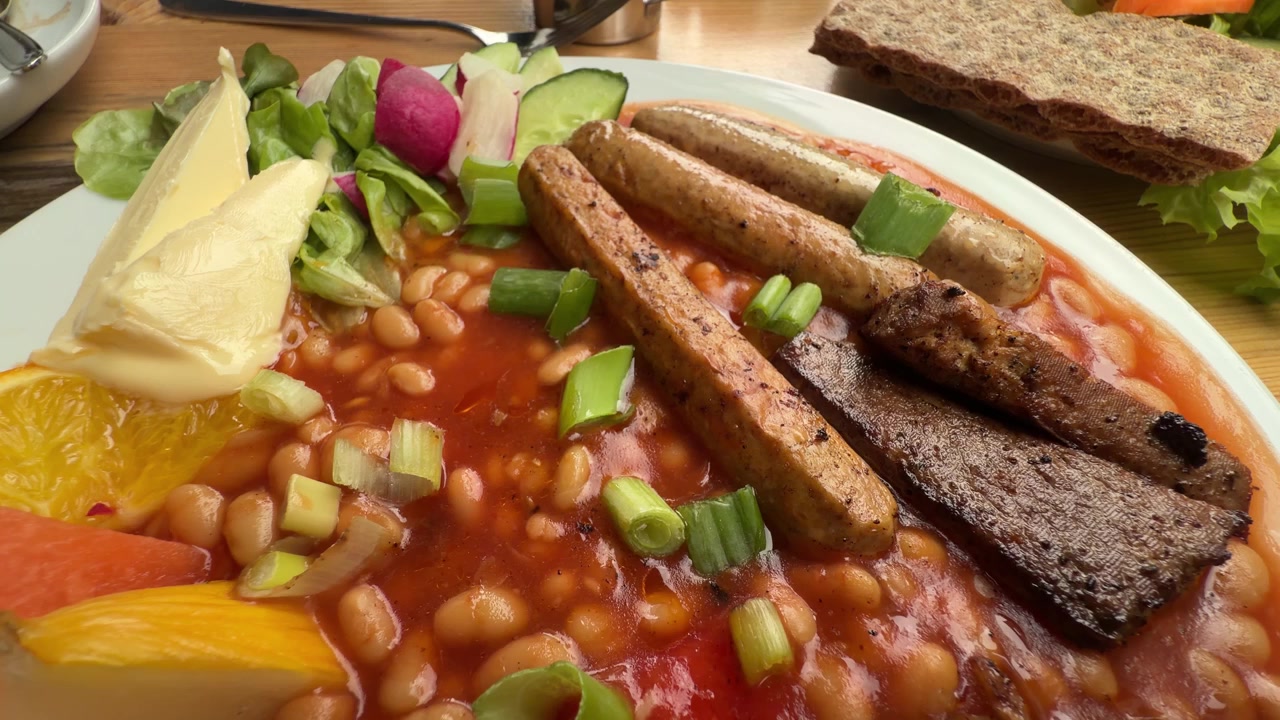 Plato de desayuno inglés con salchichas, frijoles, ensalada y pan crujiente sobre la mesa