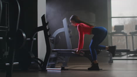 The-female-in-short-pink-top-is-working-on-her-back-in-the-gym.-Overcast-is-a-perfect-time-for-training-in-fitness-center.