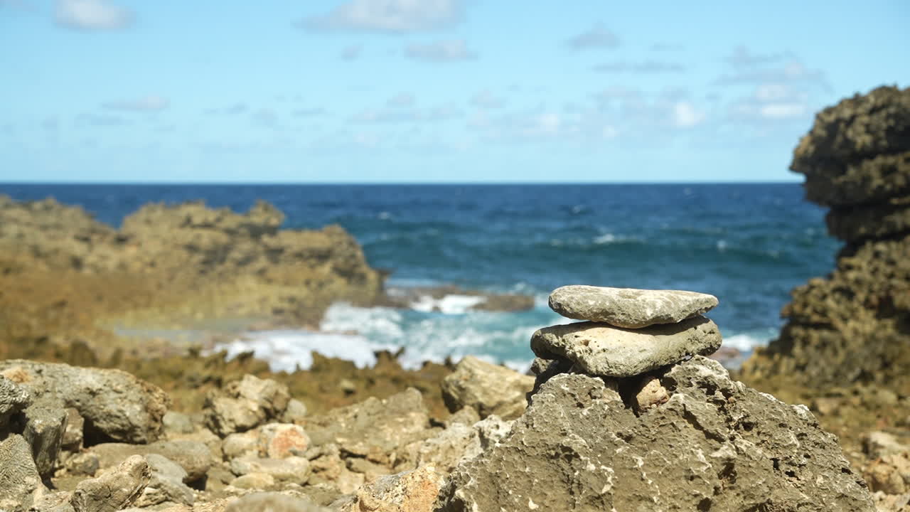 바위에 부딪히는 파도, 전경에는 납작한 돌들이 클로즈업되어 쌓여 있고, 배경에는 대서양 바다와 파도가 있어요.
