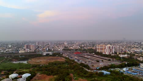 aerial view of chennai mofussil bus terminus (cmbt) and its broader urban environment. the bus terminal is a central feature, surrounded by a mix of green areas, roads, and other infrastructure