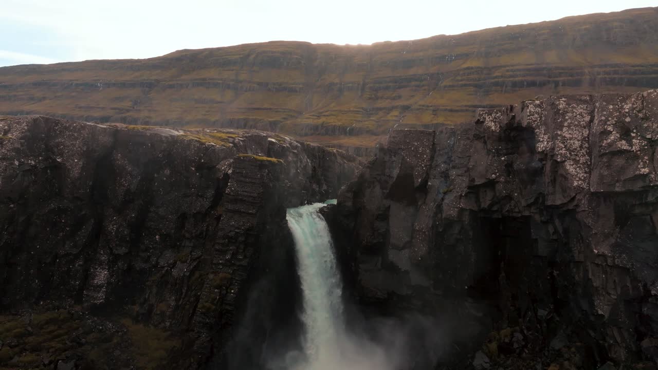 catarata en cascada desde un acantilado de lava de basalto en islandia en otoño al atardecer - revelación aérea de retroceso