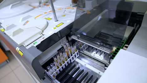 test tubes filled with blood are placed into the apparatus. medical vials are moving in the equipment at science hospital laboratory.