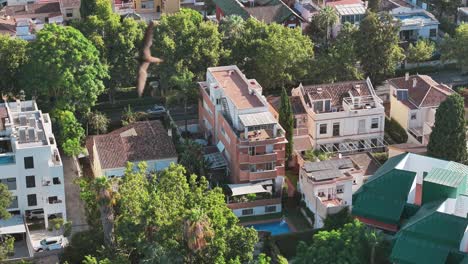 an aerial drone shot captures a modern residential building with a brick facade and traditional tiled roofs in málaga, spain. the video highlights the contrast of urban architecture and design