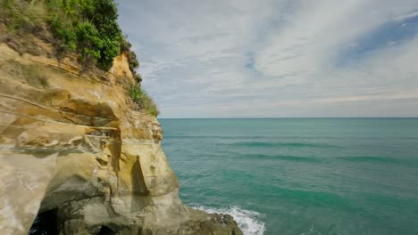 flying around corner of coastal cliff revealing three sisters rock column