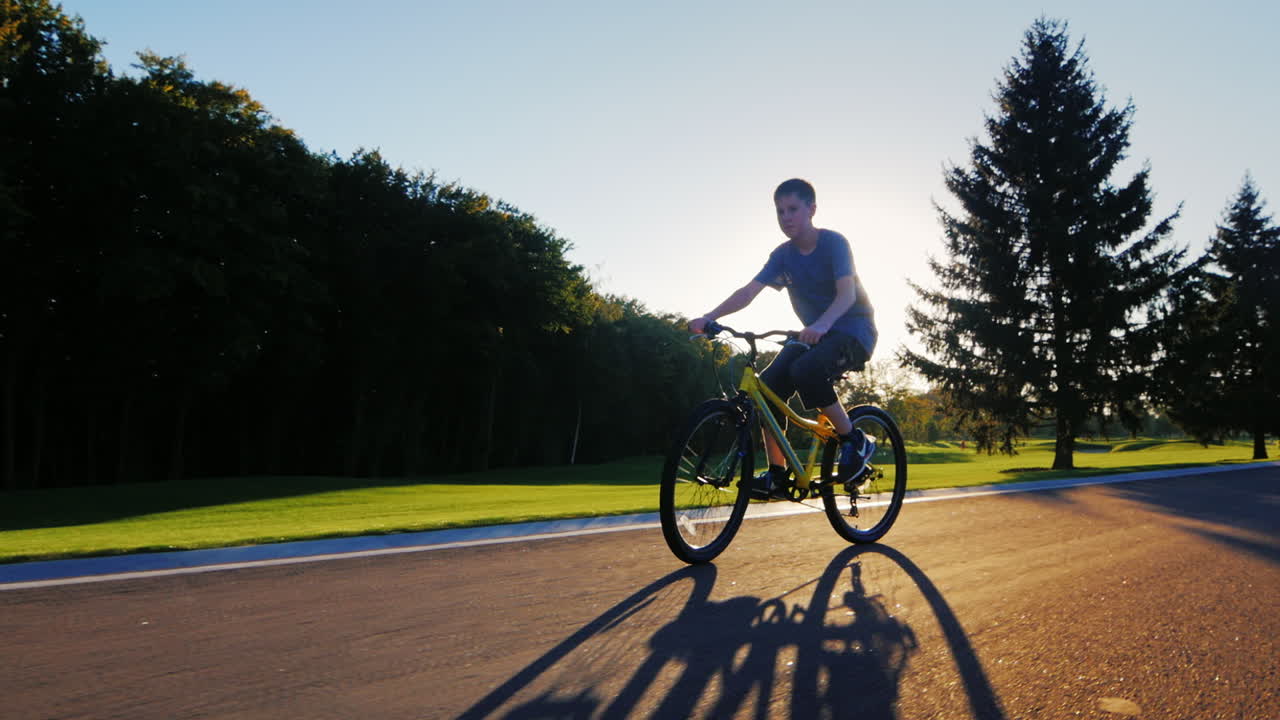 실루엣 십 대는 석양을 배경으로 평평한 길을 간다