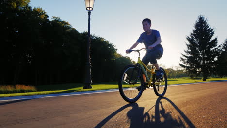 silhouette teenager goes on a flat road against the setting sun