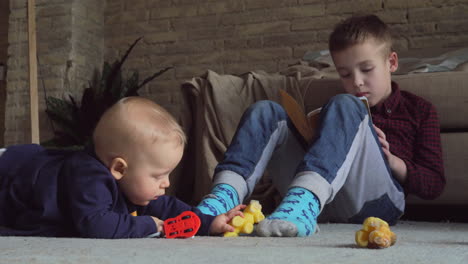 older brother playing with younger baby girl