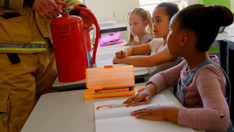 Caucasian-male-firefighter-teaching-schoolkids-about-fire-safety-in-classroom-4k