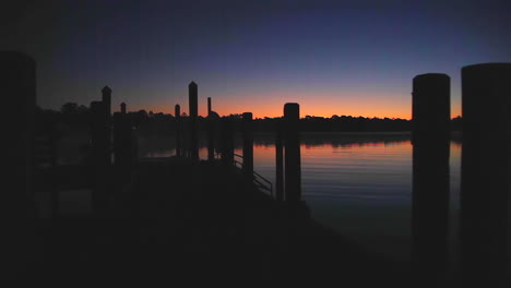 Kamerafahrt-über-Ein-Flussdock-In-Der-Silhouette-Bei-Sonnenaufgang