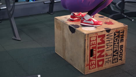 girl is jumping in the gym female athlete is performing box jumps at gym with focus on legs