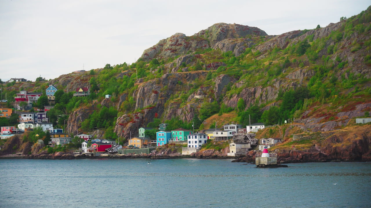Floating over quaint little town on edge of ocean backing onto large cliff on a cloudy autumn day. St Johns Newfoundland, Canada