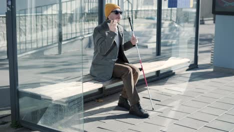 blinded man waiting for bus at a bus station