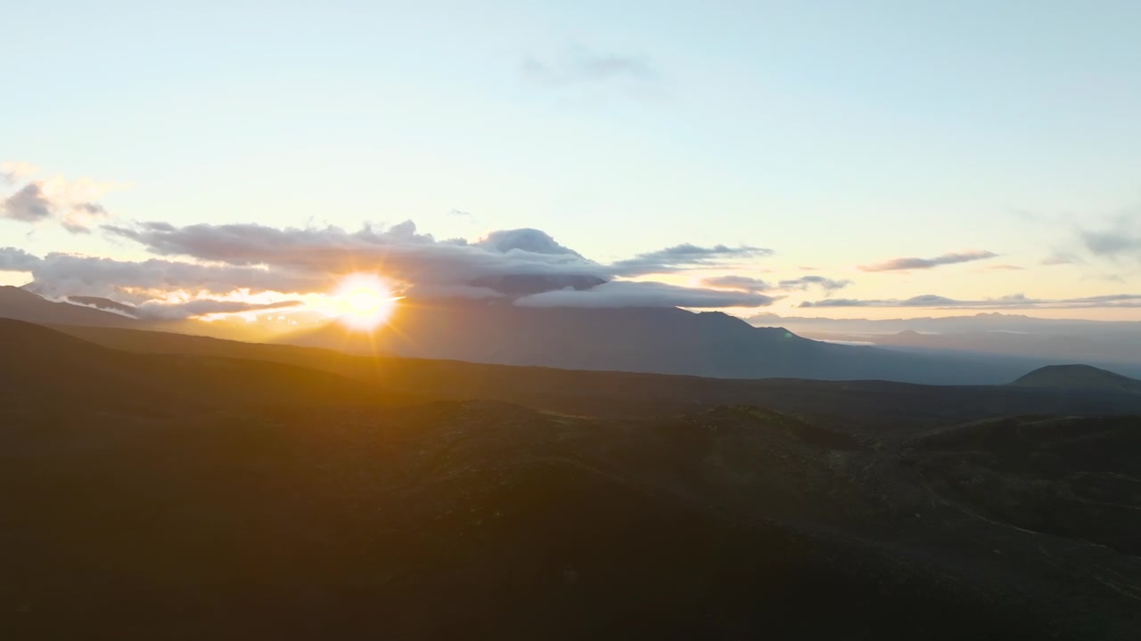 Malerischer Sonnenaufgang über dem Vulkantal Tolbatschinski Dol mit dunklen Lavafeldern, geschichteten Bergkämmen und dramatischen Wolken, Region Kamtschatka, Russland.
