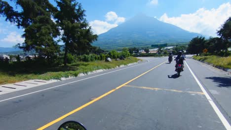 motorcycle pov group coming down from mountains towards volcano mountain