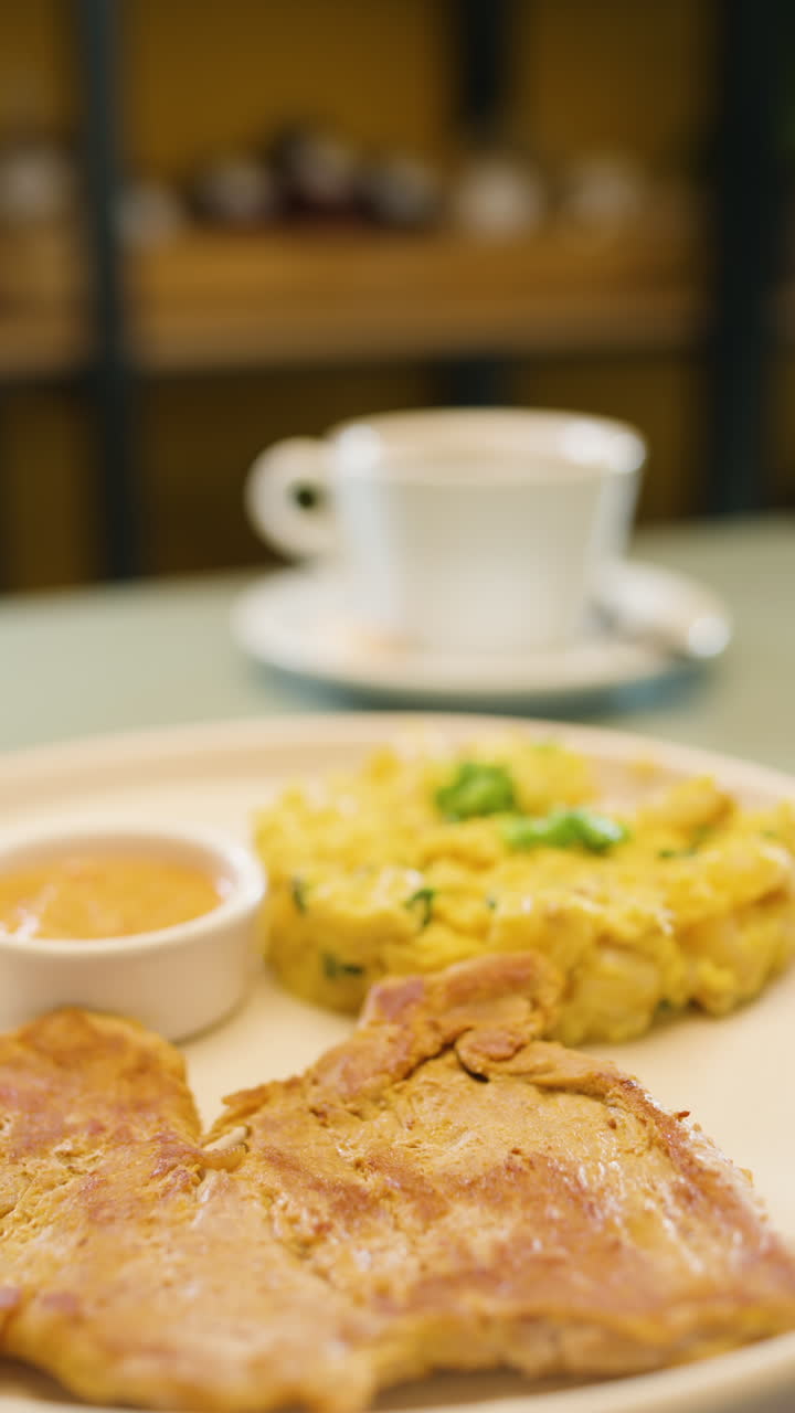 Breakfast plate with mote pillo, accompaniments and sauce in the foreground, with a cup of coffee and roast meat out of focus in the background