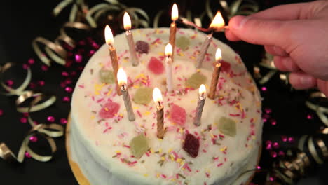 hand lighting candles on birthday cake