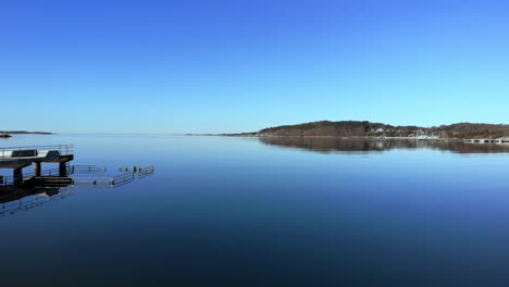 Bathing-Pier-In-Askimsbadet-Beach-With-A-Calm-Blue-Sea-And-Coastal-Mountain-Reflections-In-Gothenburg,-Sweden