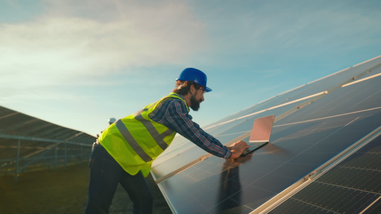Engineer inspecting solar panels with a laptop