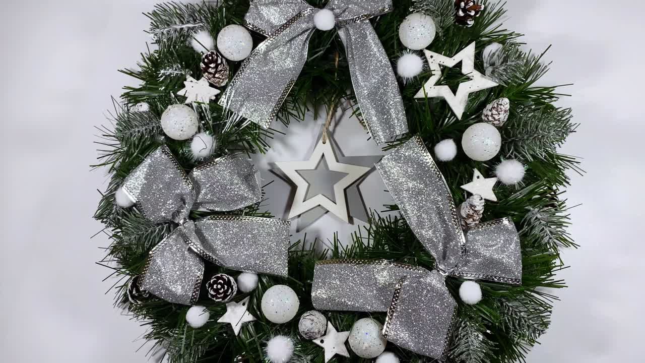 크리스마스 문 앞을 장식하는 크리스마스 꽃받침은 색 배경에 고립 된 스프루스, 은 활, 별 및 크리스마스 공으로 만들어졌습니다.