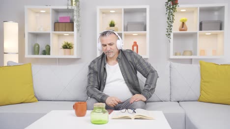 el anciano escuchando música con auriculares es infeliz y triste.