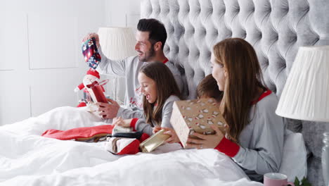 Aufgeregt-Liegt-Die-Familie-Zu-Hause-Im-Bett-Und-öffnet-Am-Weihnachtstag-Gemeinsam-Geschenke