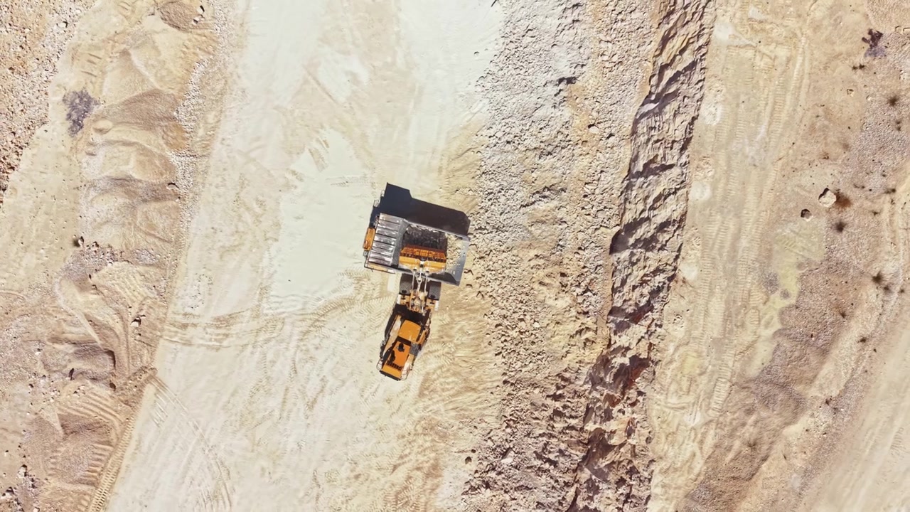 Work in a quarry with heavy machinery moving materials during the day