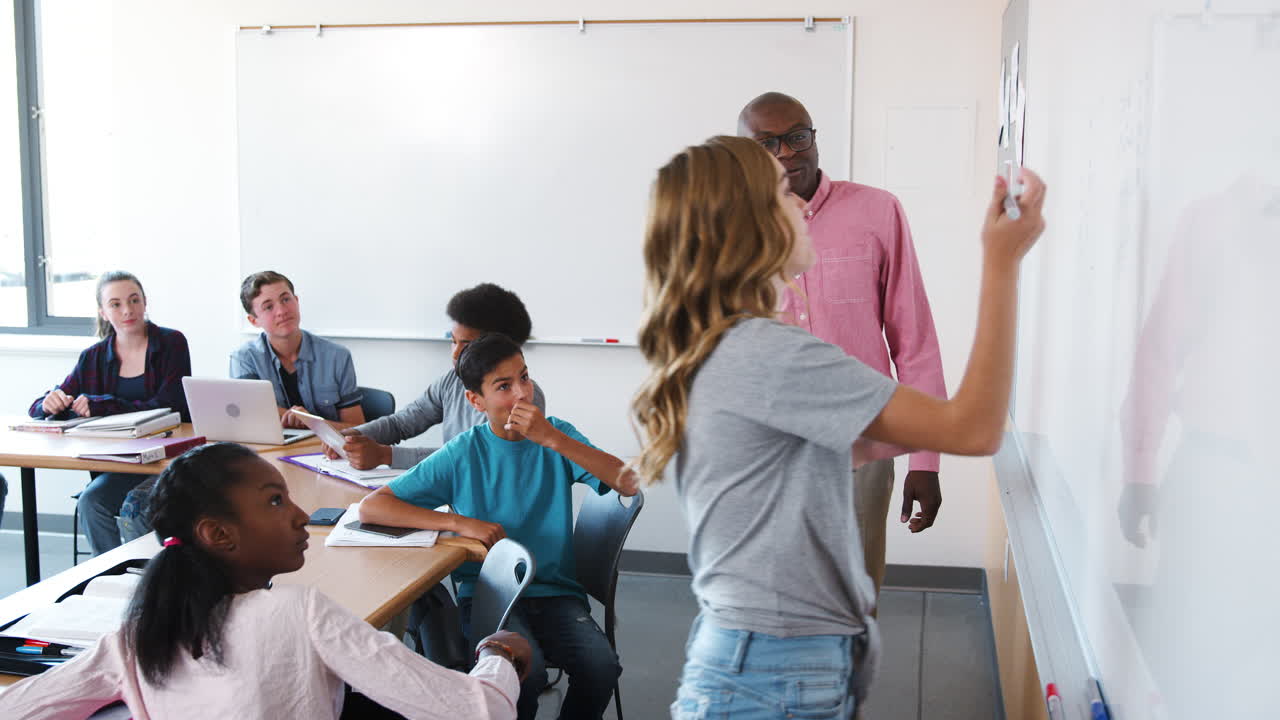 alumnos de secundaria escribiendo en la pizarra en la clase de matemáticas