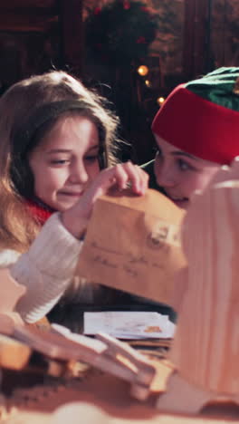 santas elf and little girl examine letters to children in a room with christmas toys. vertical video