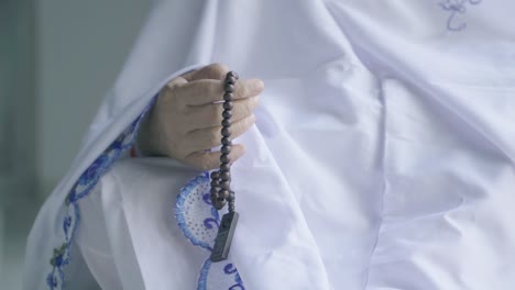 elderly woman hands holding beads during praying