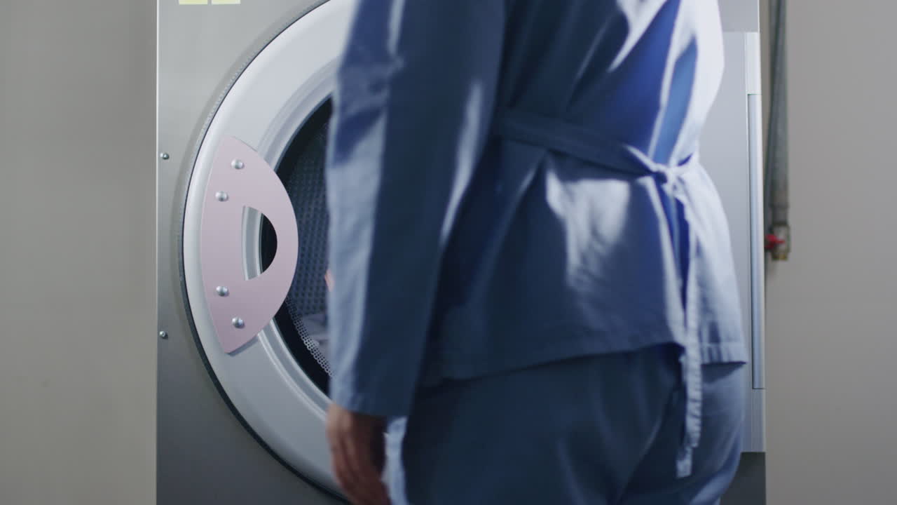 산업용 세탁기 에서 유니폼 을 로드 하는 여자