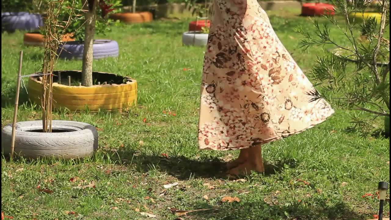 재활용 된 타이어 와 함께 정원에서 고 있는 꽃 드레스 의 여자