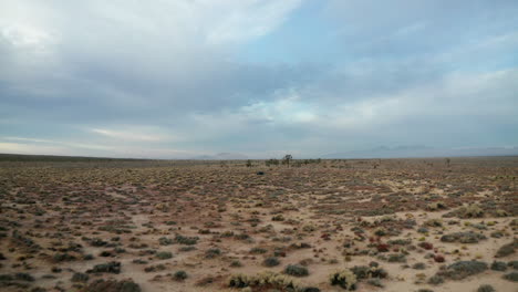 Low-altitude-push-forward-along-the-flat-Mojave-basin-to-reveal-a-jeep-in-the-desolate-landscape