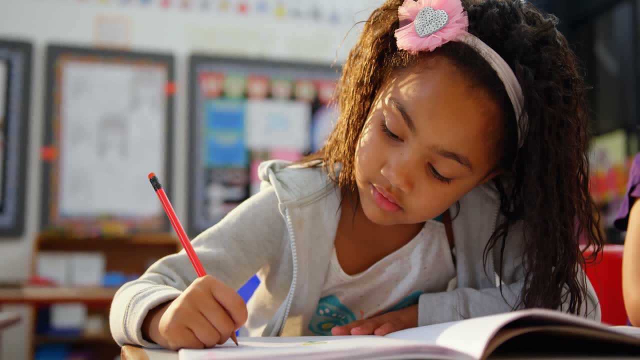 Front view of African american schoolgirl drawing on notebook in the classroom 4k