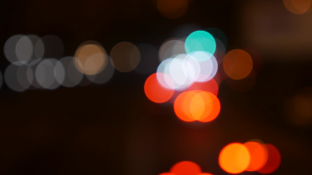 hermoso bokeh brillante en el fondo oscuro borroso por la noche. el redondo bokeh colorido brilla de las luces de los coches en la calle de la ciudad. fuera de foco con borroso. luces de la ciudad sin enfoque. bokeh de tráfico. concepto abstracto