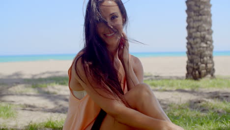 Attractive-Woman-Sitting-at-Grassy-Beach-Ground