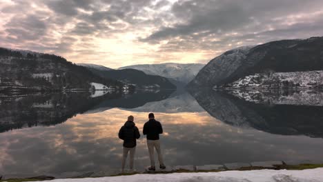 2 amigos mirando el reflejo mágico en el lago de montaña