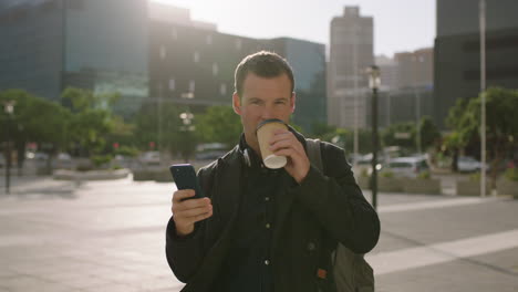 portrait of attractive young caucasian businessman texting browsing using smartphone social media app drinking coffee beverage urban city background