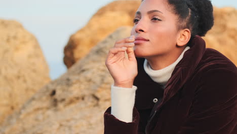 una chica afroamericana sonriente mirando a la cámara junto al mar.