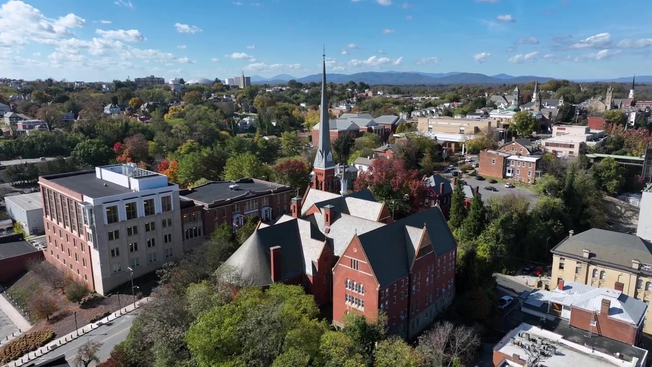 Historisk kirke i amerikansk by på en solrig efterårsdag. Rød murstensbygning med tårn i Vermont, USA. Luftoptagelse i kredsløb.