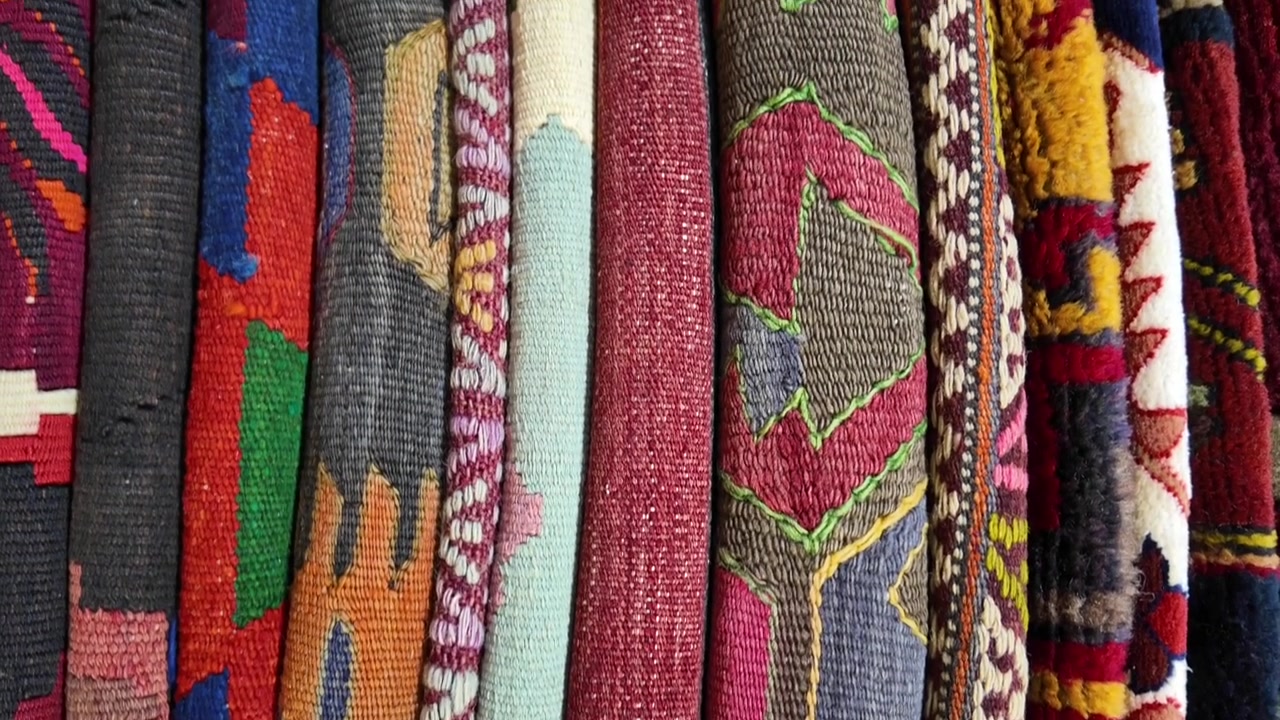 Colorful Handwoven Traditional Rugs and Textiles Displayed in a Market
