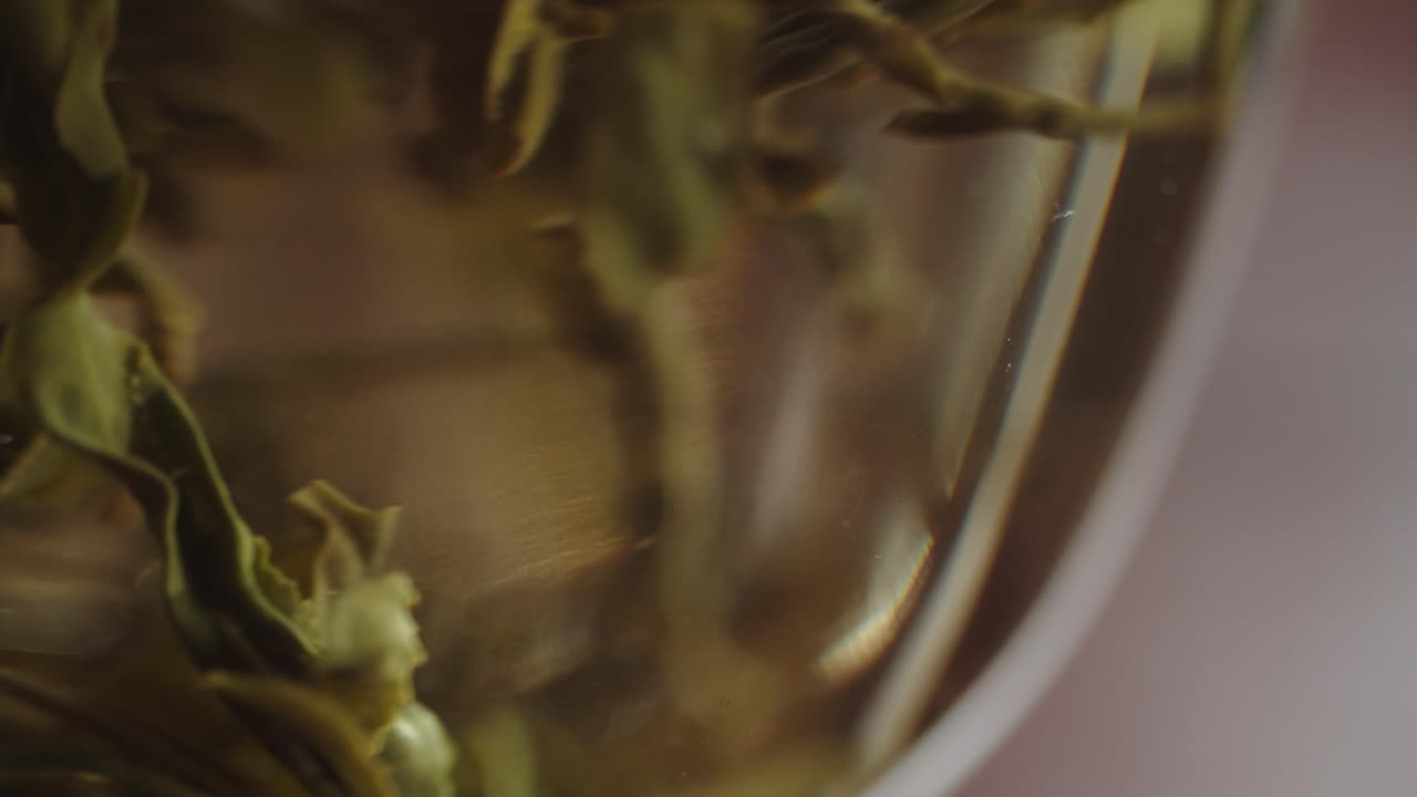 Chinese green tea leaves infused in hot water inside traditional glass gaiwan bowl